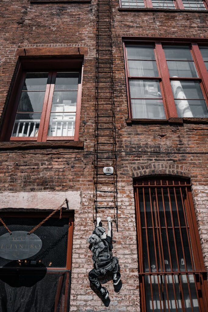 Creative mural depicting a climber on a vintage urban brick facade.